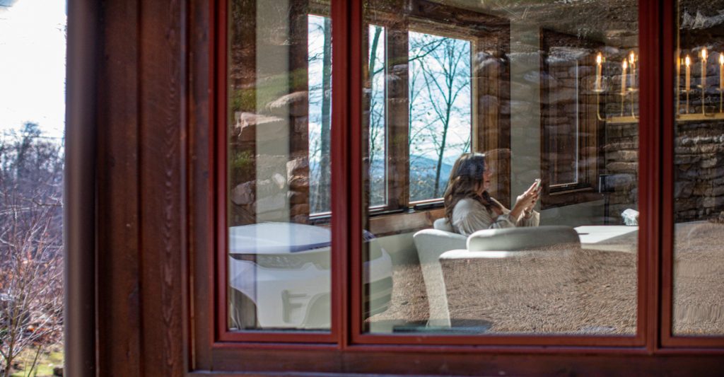 woman behind window, using cell phone while sitting on couch
