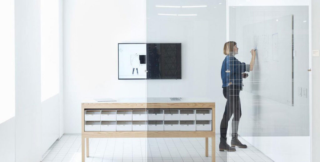 woman working in a conference room with glass walls behind cloaking film