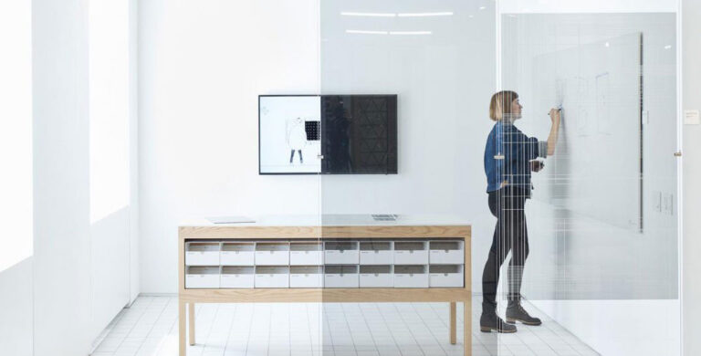 woman working in a conference room with glass walls behind cloaking film
